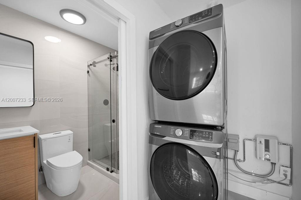 A bathroom features a stacked Samsung washer and dryer unit next to a glass shower — 570 NW 48th St # B, Miami FL 33127, MIAMI, FL