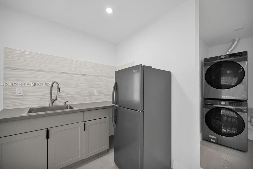 A laundry room features a sink, a refrigerator, and a stacked washer and dryer unit — 570 NW 48th St # B, Miami FL 33127, MIAMI, FL