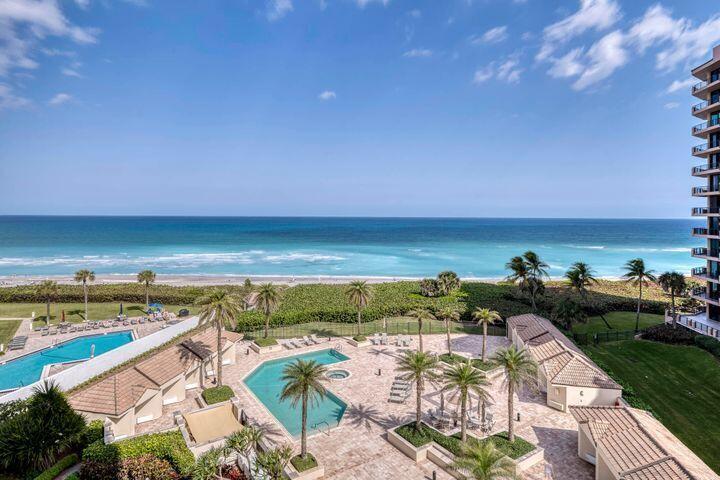 An elevated view of a coastal resort pool deck with palm trees and the ocean — 570 Ocean Drive # 601, Juno Beach FL 33408, JUNO BEACH, FL