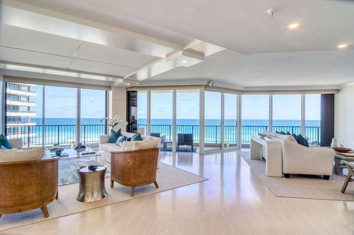 A bright living room features light wood floors, neutral furniture, and floor-to-ceiling windows overlooking the ocean — 570 Ocean Drive # 601, Juno Beach FL 33408, JUNO BEACH, FL
