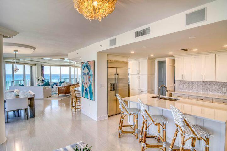 An open-concept kitchen and dining area with white cabinetry, a kitchen island, and ocean views — 570 Ocean Drive # 601, Juno Beach FL 33408, JUNO BEACH, FL
