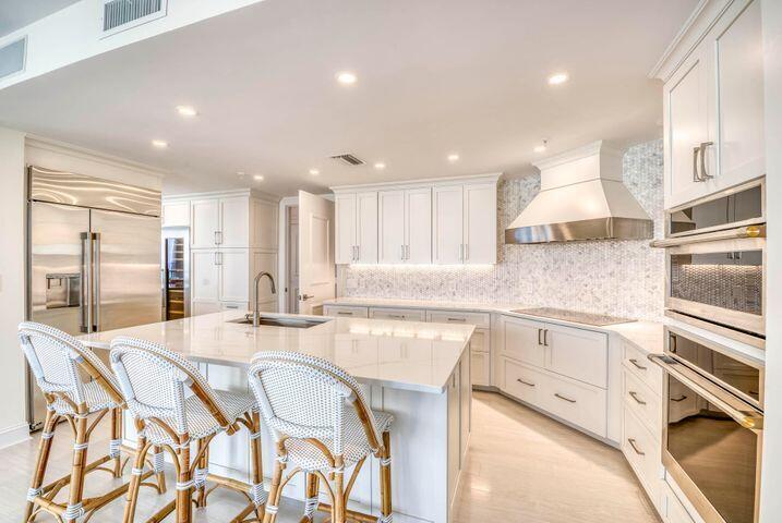 A bright, modern kitchen features white cabinetry, a large marble island, and stainless steel appliances — 570 Ocean Drive # 601, Juno Beach FL 33408, JUNO BEACH, FL