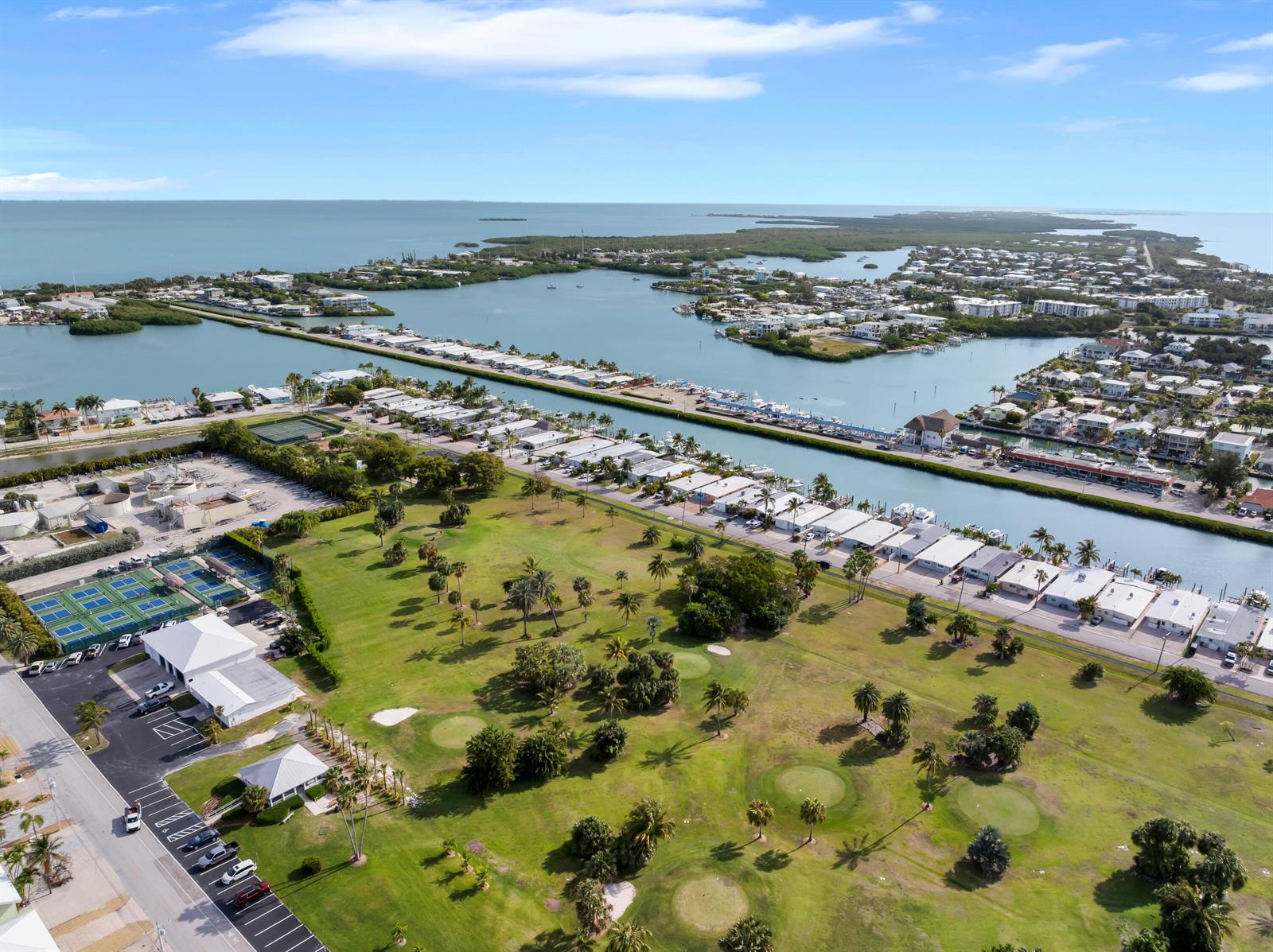 An aerial view shows a golf course, residential buildings, and a canal near the ocean — 34 7th Street, FL 33051, FL
