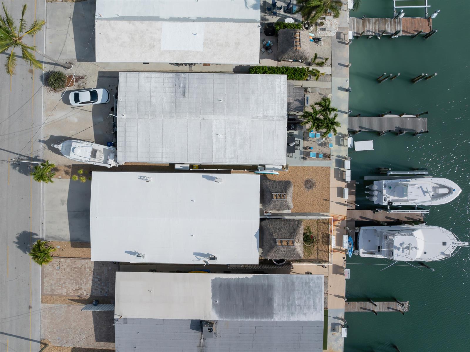 An aerial view shows several waterfront homes with boat docks and parked vehicles — 34 7th Street, FL 33051, FL