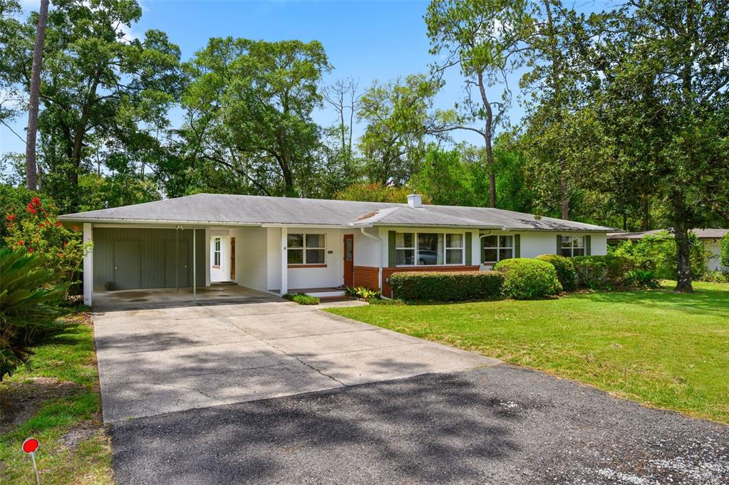 A single-story house with a carport, white siding, brick accents, and a concrete driveway — 3919 SW 4TH PLACE, GAINESVILLE, FL