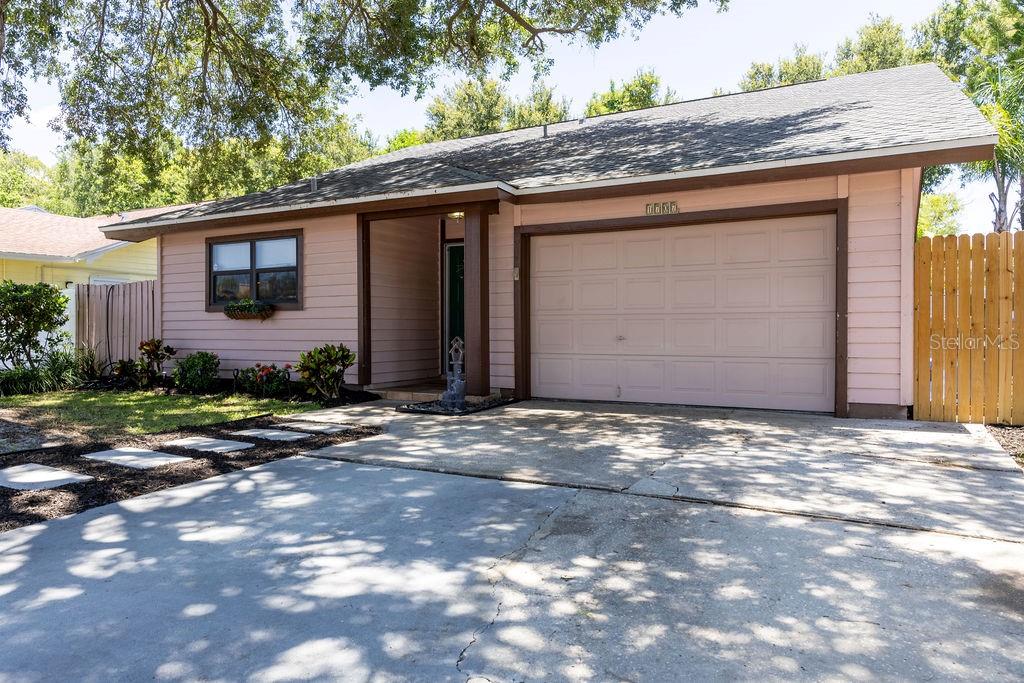 A single-story house with pink siding, a one-car garage, and a concrete driveway — 1707 WHISPERING DRIVE E, LARGO, FL