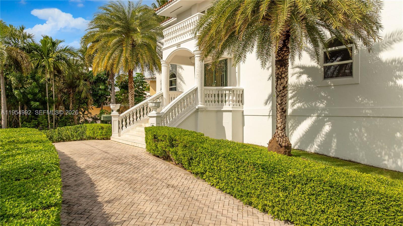 A paved driveway leads to the white exterior of a house with a raised entrance — 6275 Dolphin Dr, Coral Gables FL 33158, CORAL GABLES, FL