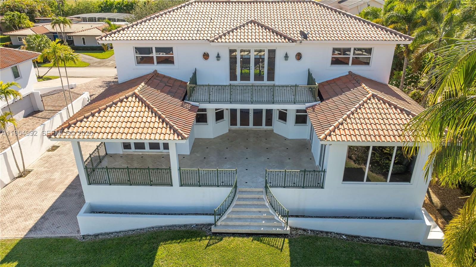 An aerial view of a two-story white house with a tiled roof and rear balcony — 6275 Dolphin Dr, Coral Gables FL 33158, CORAL GABLES, FL