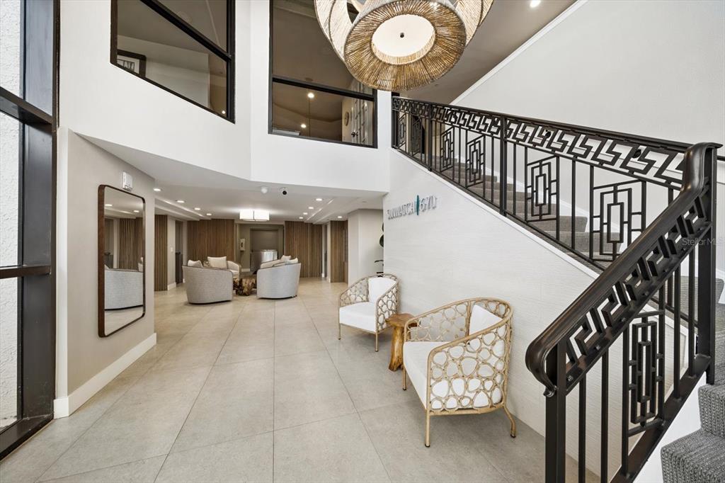 A living room with a sofa, armchairs, coffee table, and large windows overlooking palm trees — 670 ISLAND WAY UNIT 304, CLEARWATER BEACH, FL