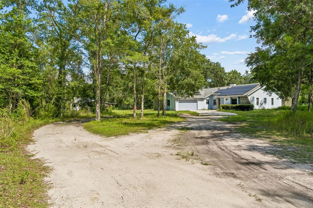 A light-colored house with solar panels sits at the end of a sandy dirt driveway — 3140 CRUM ROAD, BROOKSVILLE, FL
