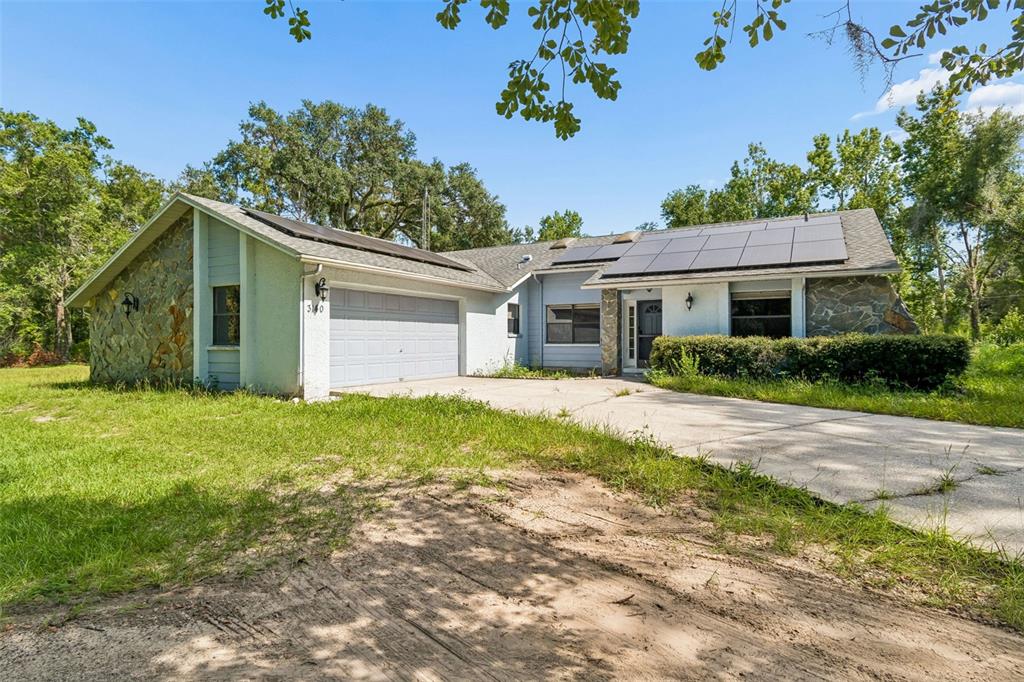 A single-story house with a stone facade, a two-car garage, and solar panels on the roof — 3140 CRUM ROAD, BROOKSVILLE, FL