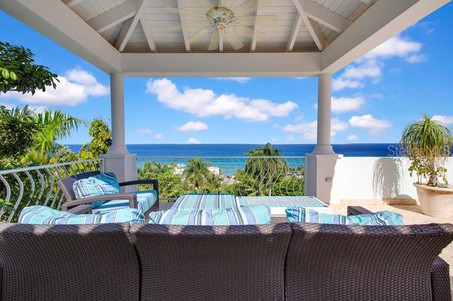 An outdoor covered patio features wicker furniture overlooking a scenic ocean view — 1 COLINA LINDA- "TRANQUILO", RINCON, PR