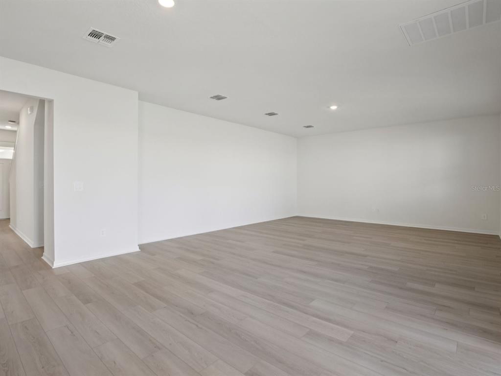 An empty room features white walls, recessed lighting, and light-colored wood-look flooring — 9017 VENETIA COURT, PALMETTO, FL