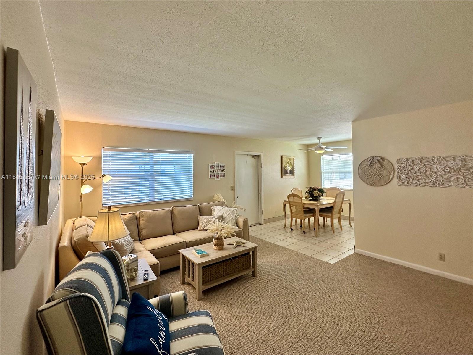 A living room with carpeted floors flows into a tiled dining area with a table — 524 Monaco K # 524K, Delray Beach FL 33446, DELRAY BEACH, FL