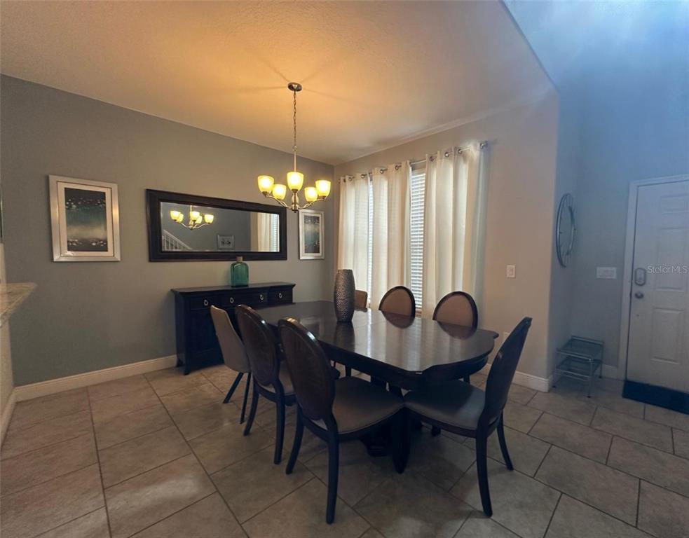 A dining room features a dark wood table, matching chairs, a sideboard, and a chandelier — 5299 WILDWOOD WAY, DAVENPORT, FL