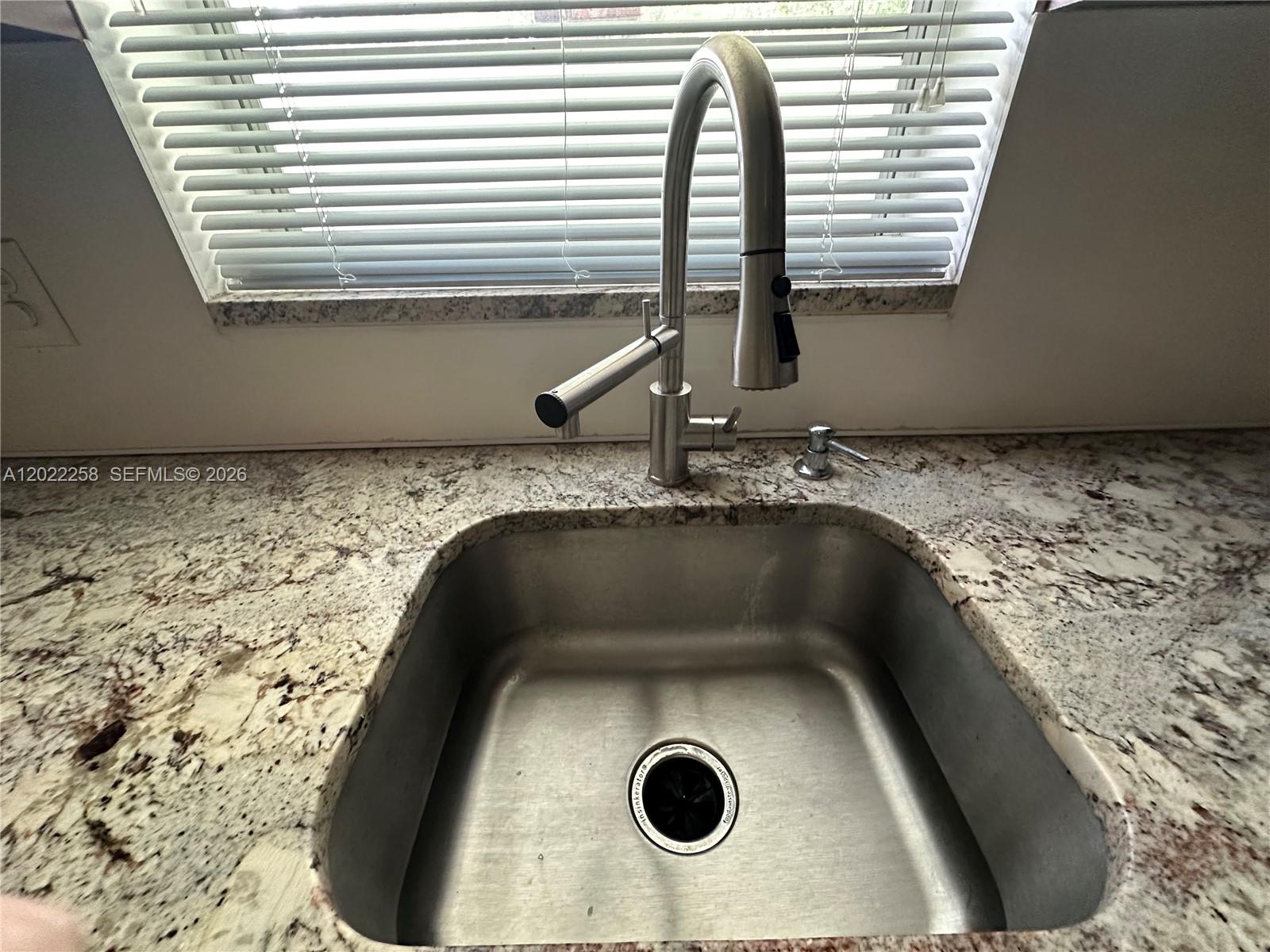 A stainless steel kitchen sink with a pull-down faucet is set in granite countertops — 3700 Harrison St # 15A, Hollywood FL 33021, HOLLYWOOD, FL