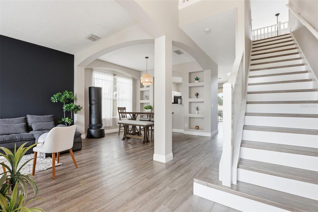 A living room with a staircase, dark accent wall, and an adjacent dining area — 100 RUBINO DRIVE, DAVENPORT, FL