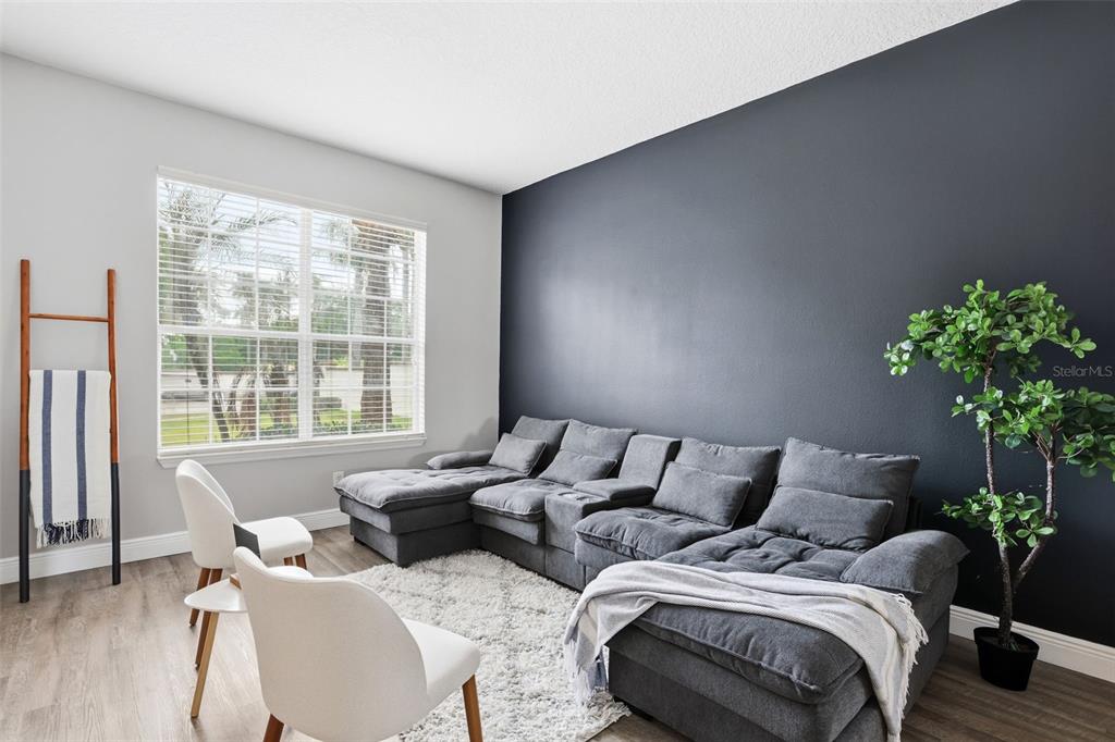 A living room features a large gray sectional sofa against a dark accent wall — 100 RUBINO DRIVE, DAVENPORT, FL