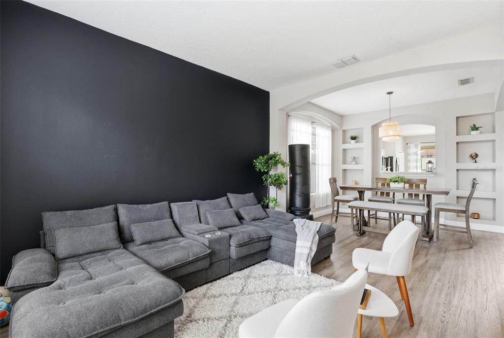 A living room features a large gray sectional, a black accent wall, and an adjacent dining area — 100 RUBINO DRIVE, DAVENPORT, FL
