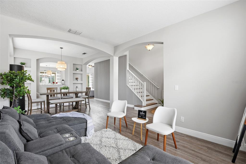 A living room with gray flooring and a sectional sofa opens to a dining area — 100 RUBINO DRIVE, DAVENPORT, FL