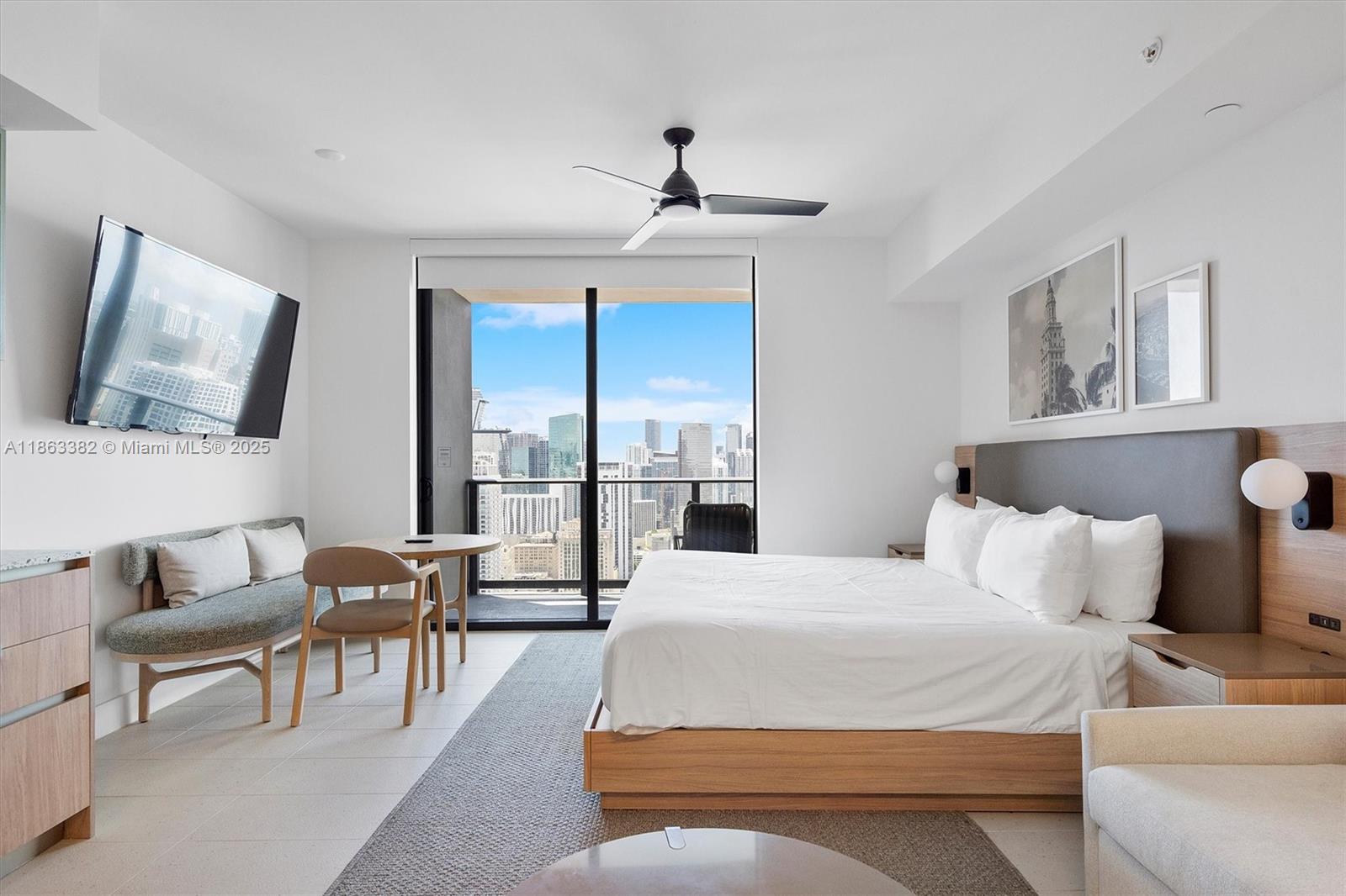 A modern bedroom features a king bed, a small dining area, and a city view balcony — 159 NE 6th St # 3806, Miami FL 33132, MIAMI, FL