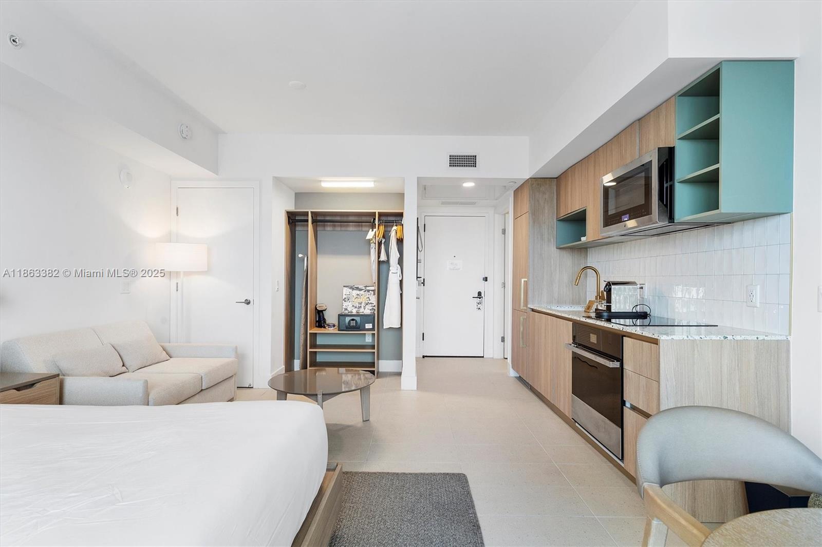 A studio apartment features a kitchenette with wood cabinets, a bed, and a small sofa — 159 NE 6th St # 3806, Miami FL 33132, MIAMI, FL