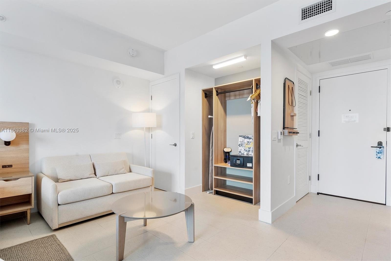 A room features a beige sofa, a round coffee table, and an open closet area — 159 NE 6th St # 3806, Miami FL 33132, MIAMI, FL