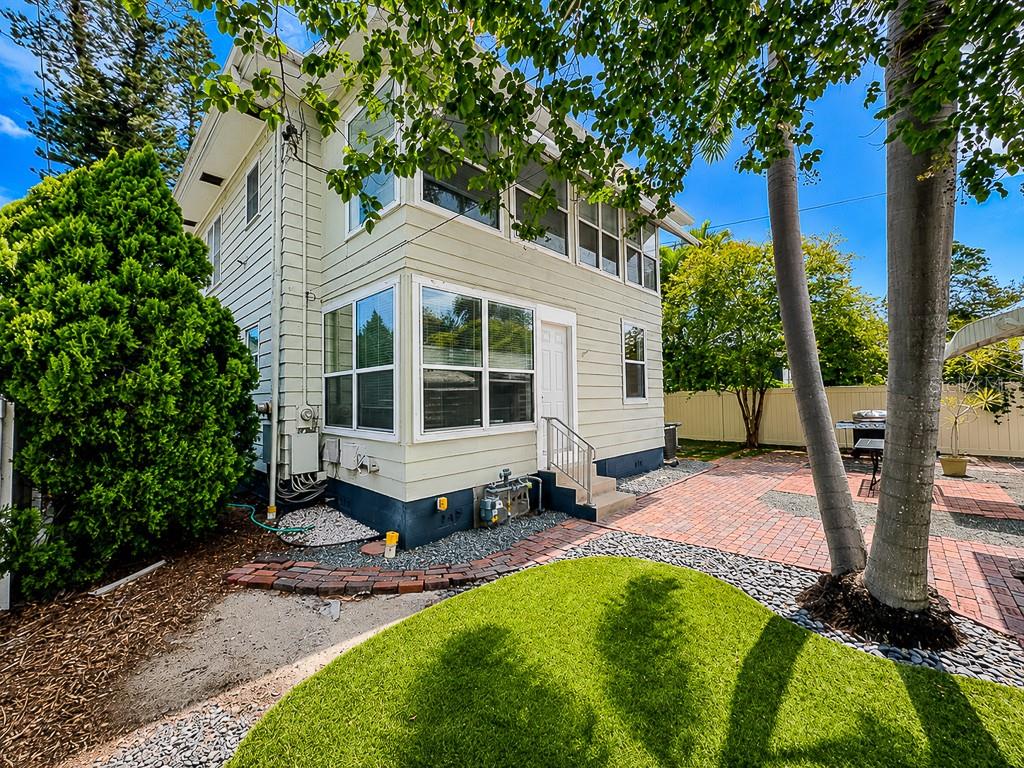 The exterior of a two-story house features light siding, large windows, and a brick patio — 400 20TH STREET N, ST PETERSBURG, FL