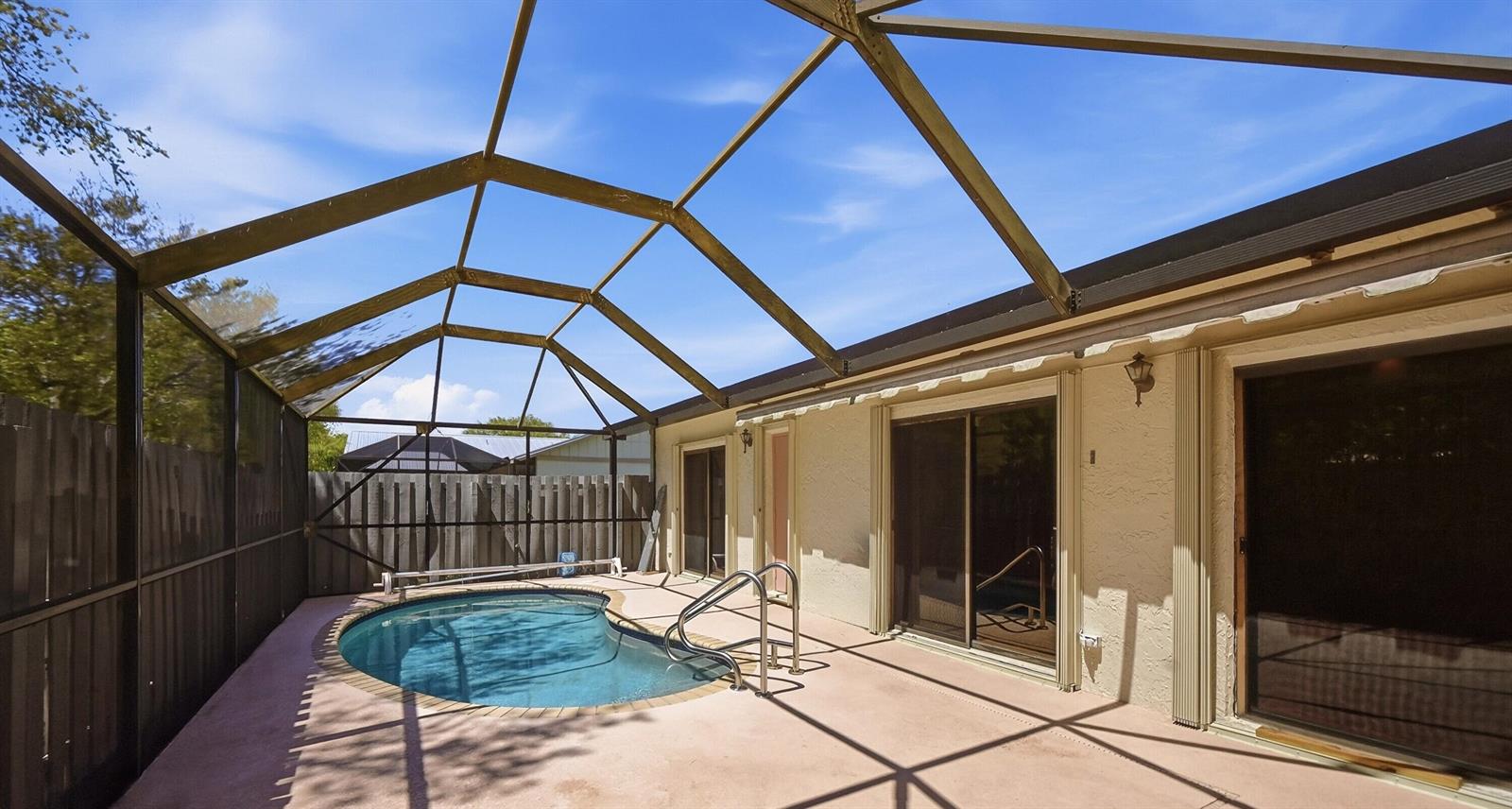 A screened-in patio features a small kidney-shaped pool and sliding glass doors to the house — 8853 Andy Court # A, Boynton Beach FL 33436, BOYNTON BEACH, FL