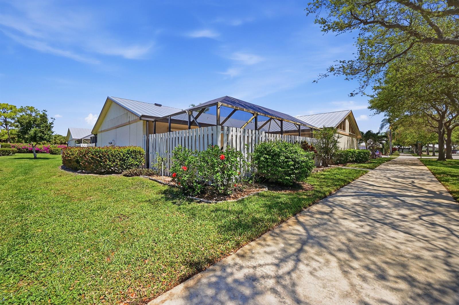 A house with a screened-in patio and a white fence sits beside a paved sidewalk — 8853 Andy Court # A, Boynton Beach FL 33436, BOYNTON BEACH, FL
