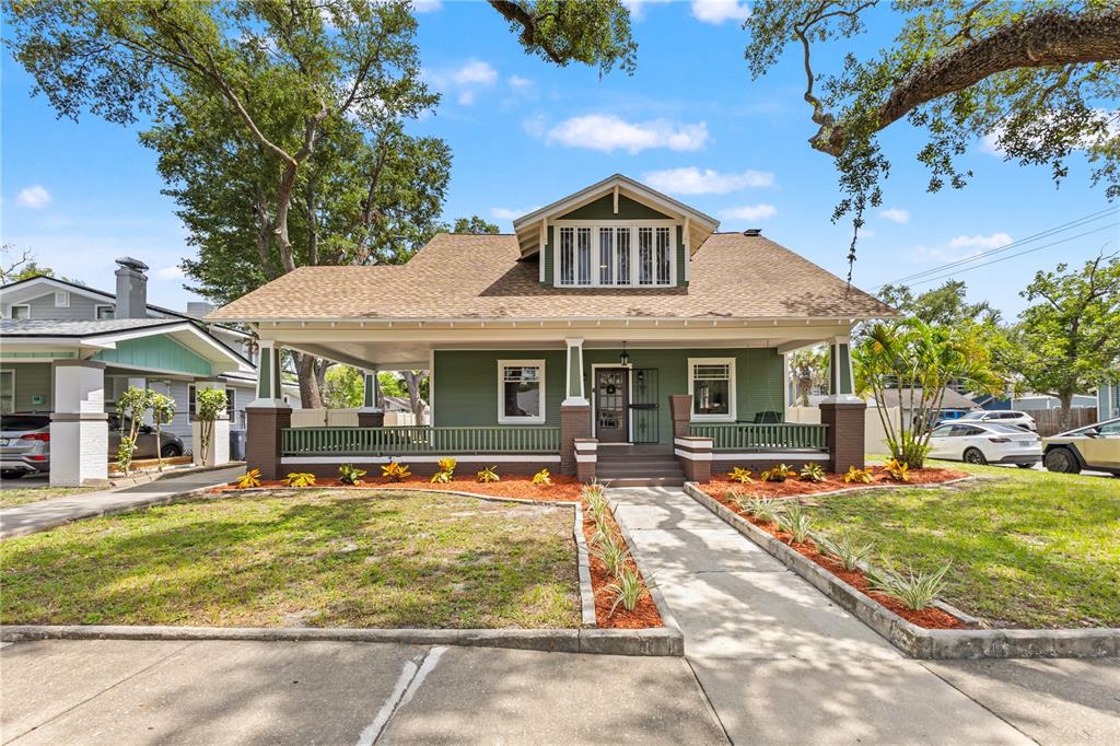 A green bungalow with a large front porch, brown trim, and a dormer window — 120 W COMANCHE AVENUE, TAMPA, FL