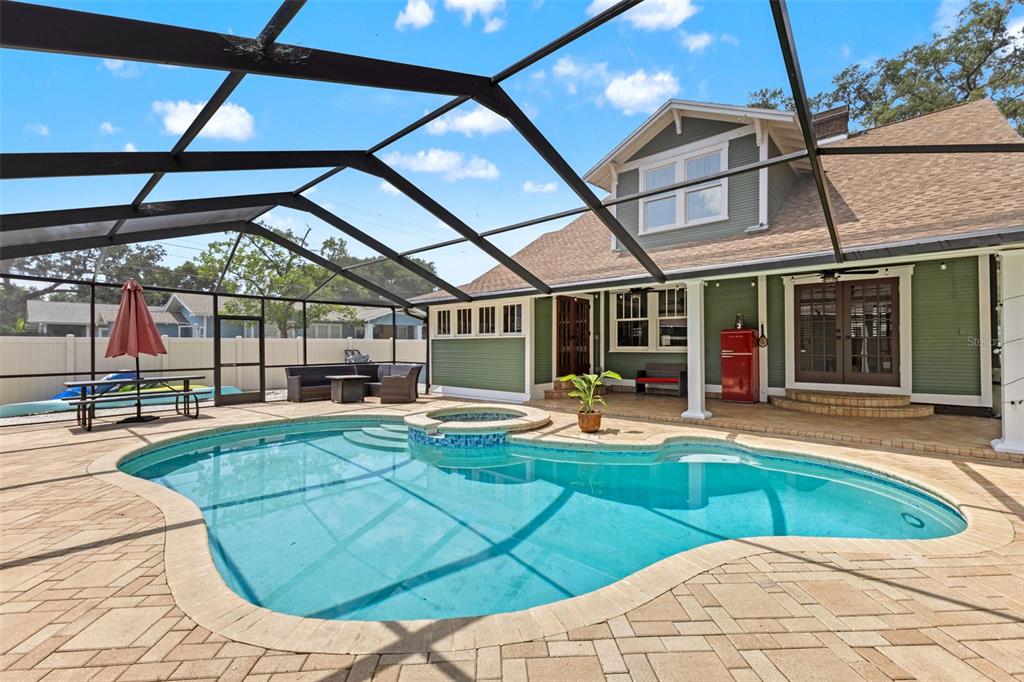 A backyard swimming pool and hot tub are enclosed by a screen cage behind a house — 120 W COMANCHE AVENUE, TAMPA, FL