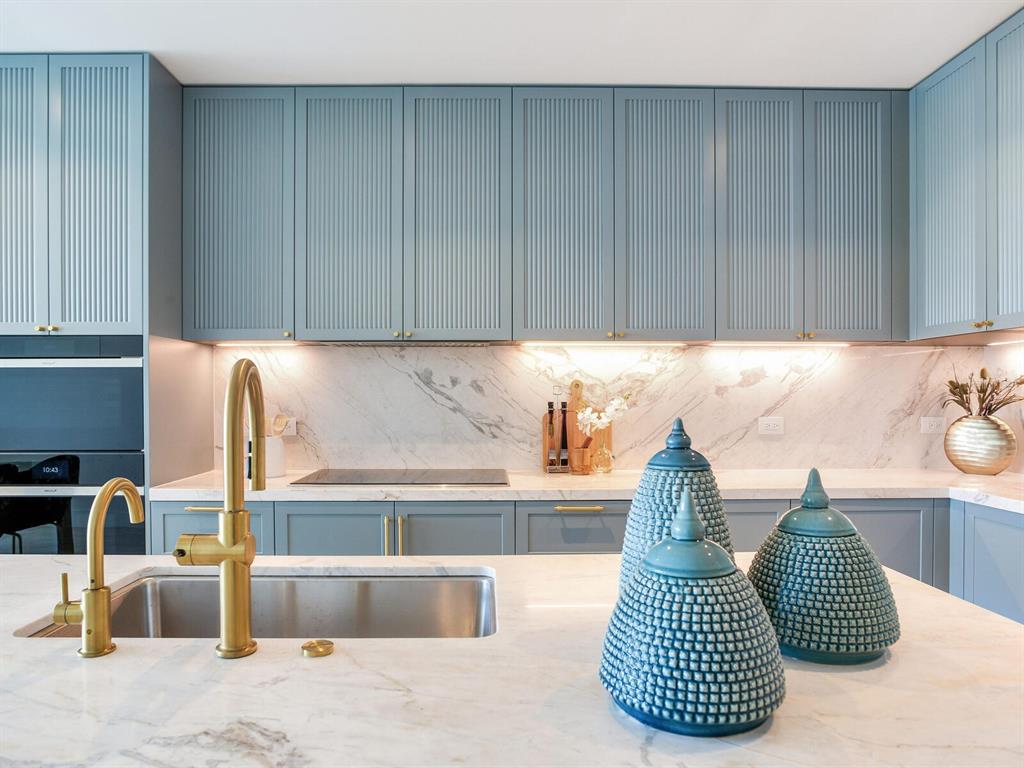 A kitchen features blue fluted cabinets, a marble countertop and backsplash, and gold fixtures — 3015 S YSABELLA AVENUE UNIT 1403, TAMPA, FL