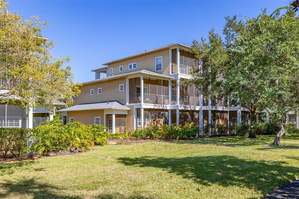 A three-story tan building with screened-in porches and a grassy lawn in the foreground — 612 RUM RUN UNIT 612, DAVENPORT, FL
