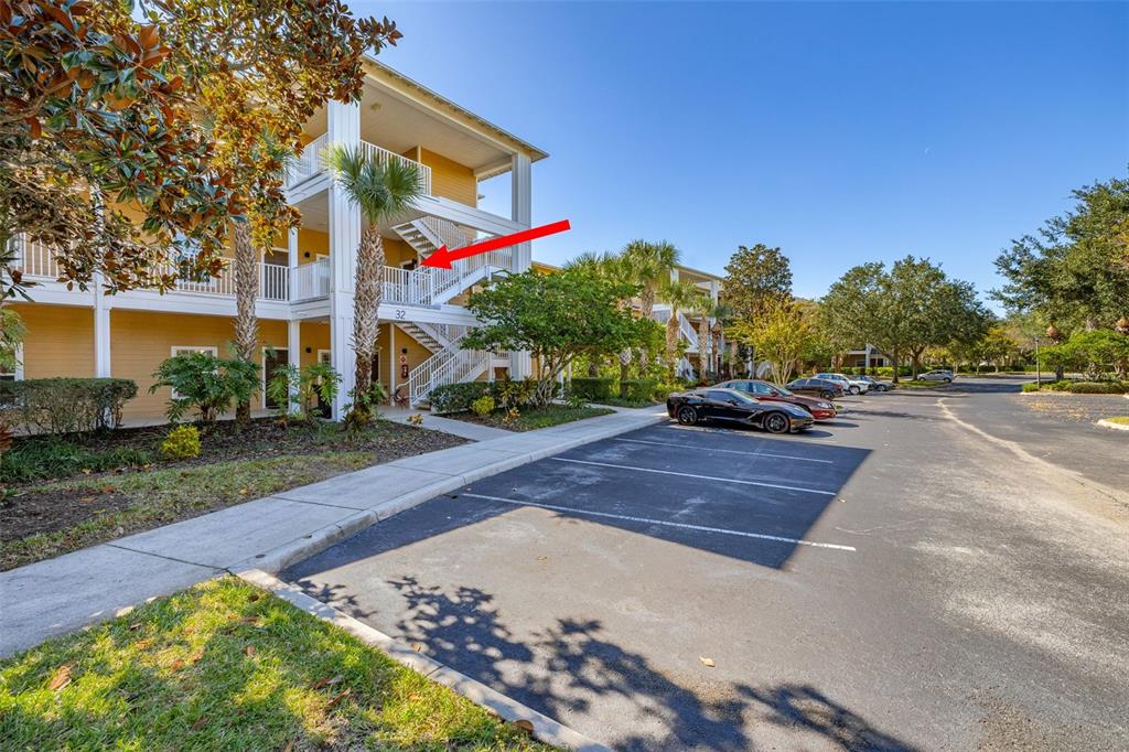 An exterior view of a multi-story apartment building with a red arrow pointing toward stairs — 612 RUM RUN UNIT 612, DAVENPORT, FL