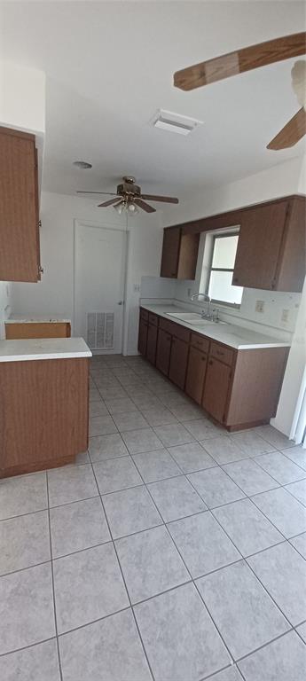 A kitchen features brown cabinets, white countertops, tiled flooring, and a ceiling fan — 68 S COLUMBUS STREET, BEVERLY HILLS, FL