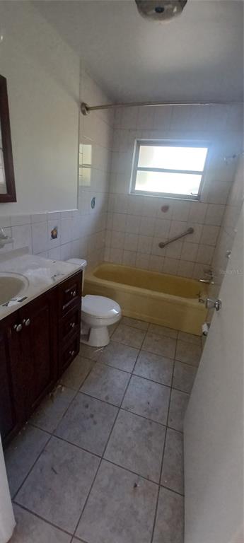 A bathroom features a dark wood vanity, a yellow bathtub, and light-colored floor tiles — 68 S COLUMBUS STREET, BEVERLY HILLS, FL