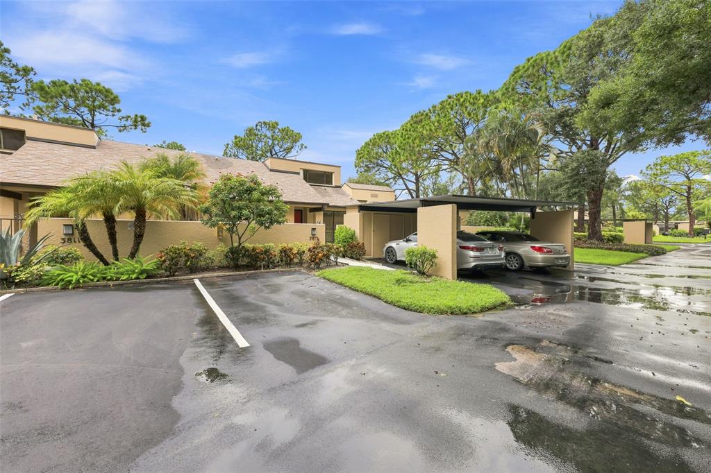 A tan townhouse exterior features a covered carport with two parked cars and landscaping — 3813 FISHING TRAIL UNIT 62, SARASOTA, FL