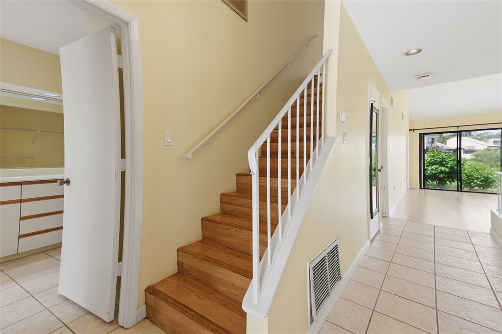 A staircase with wooden treads and a white railing sits beside a tiled entryway — 3813 FISHING TRAIL UNIT 62, SARASOTA, FL