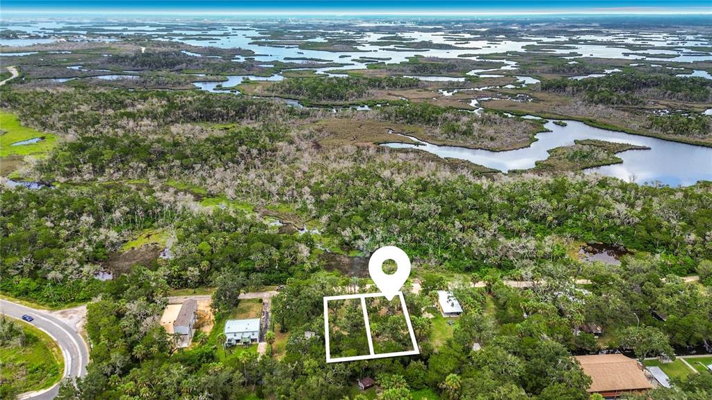 An aerial view shows a wooded lot outlined in white near a coastal marshland — 14328 W SUTTON COURT, CRYSTAL RIVER, FL