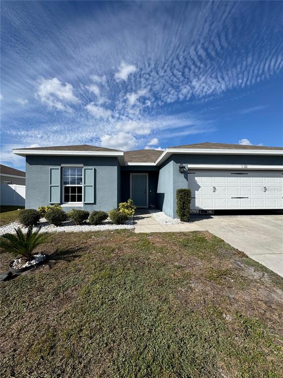A blue single-story house features a white garage door and a front entrance — 1666 AMBAR COURT, WINTER HAVEN, FL