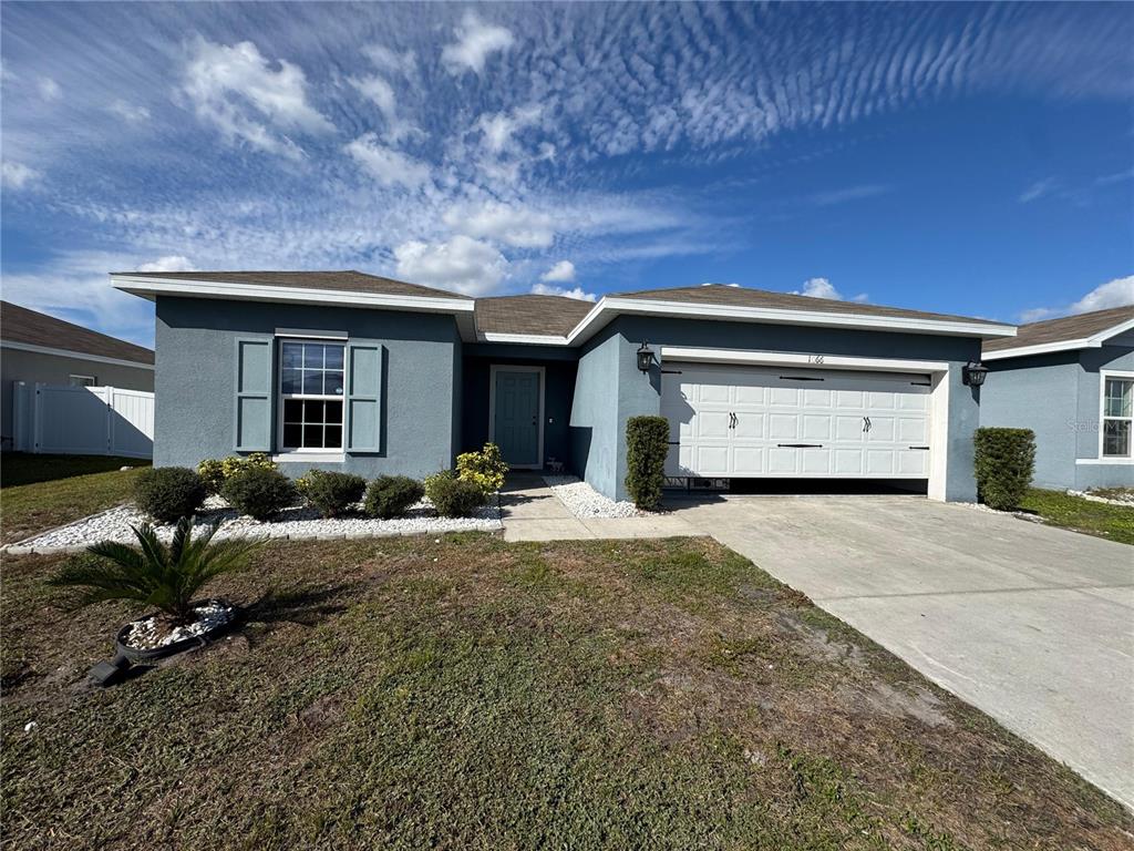 A single-story blue house with a two-car garage and a concrete driveway — 1666 AMBAR COURT, WINTER HAVEN, FL