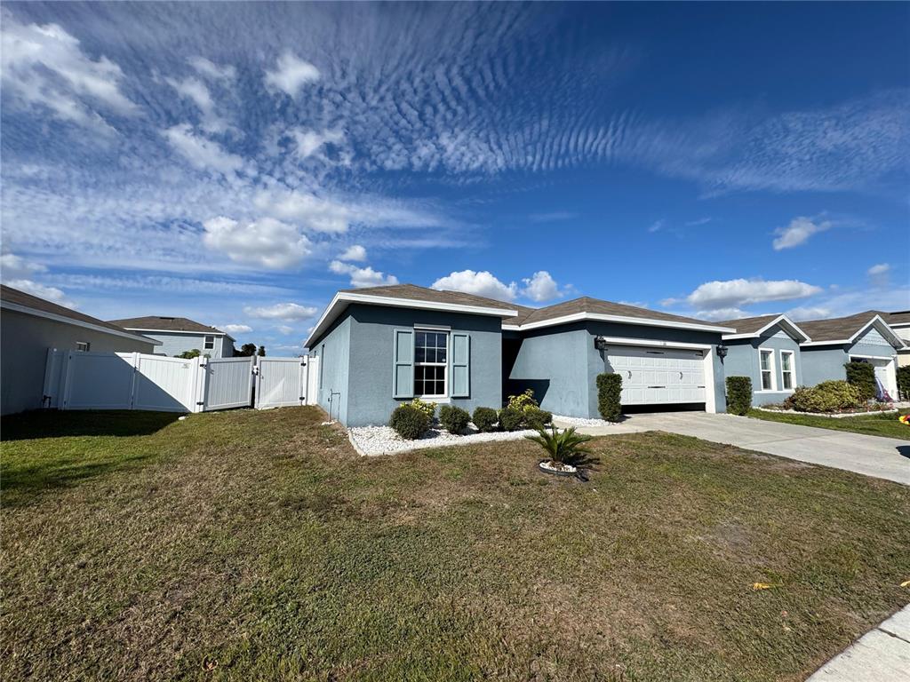 A blue single-story house with a white garage door and a white vinyl fence — 1666 AMBAR COURT, WINTER HAVEN, FL
