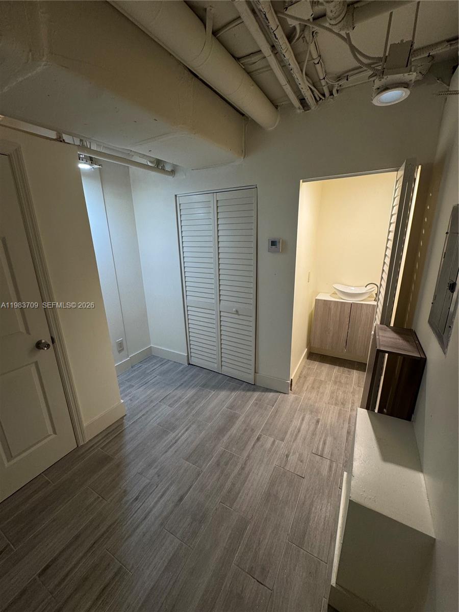 A small room features gray wood-look tile flooring, a louvered closet, and an open vanity — 110 Washington Ave # 7, Miami Beach FL 33139, MIAMI BEACH, FL