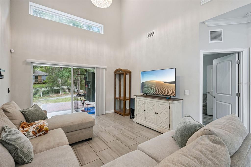 A living room with high ceilings, tile floors, a sectional sofa, and a sliding glass door — 500 E EUCLID AVENUE, DELAND, FL