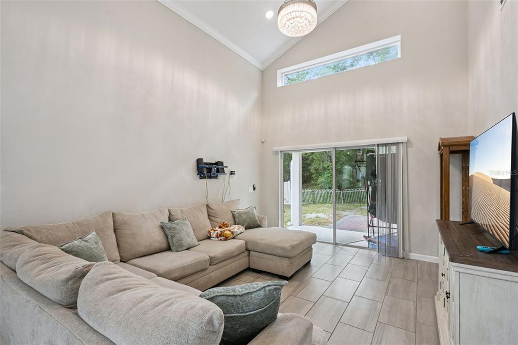 A living room features a sectional sofa, tile flooring, vaulted ceilings, and a sliding glass door — 500 E EUCLID AVENUE, DELAND, FL