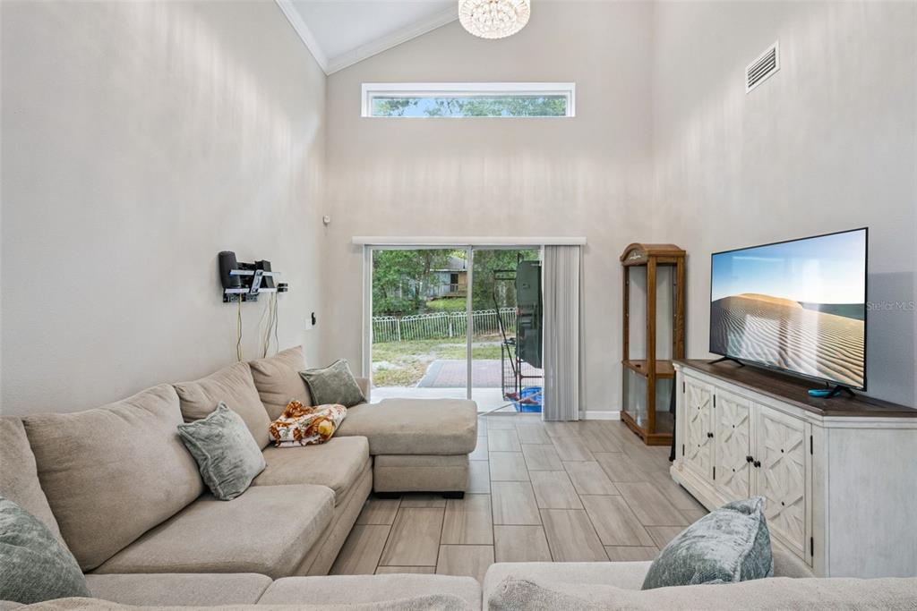 A living room features a sectional sofa, a television on a cabinet, and sliding glass doors — 500 E EUCLID AVENUE, DELAND, FL