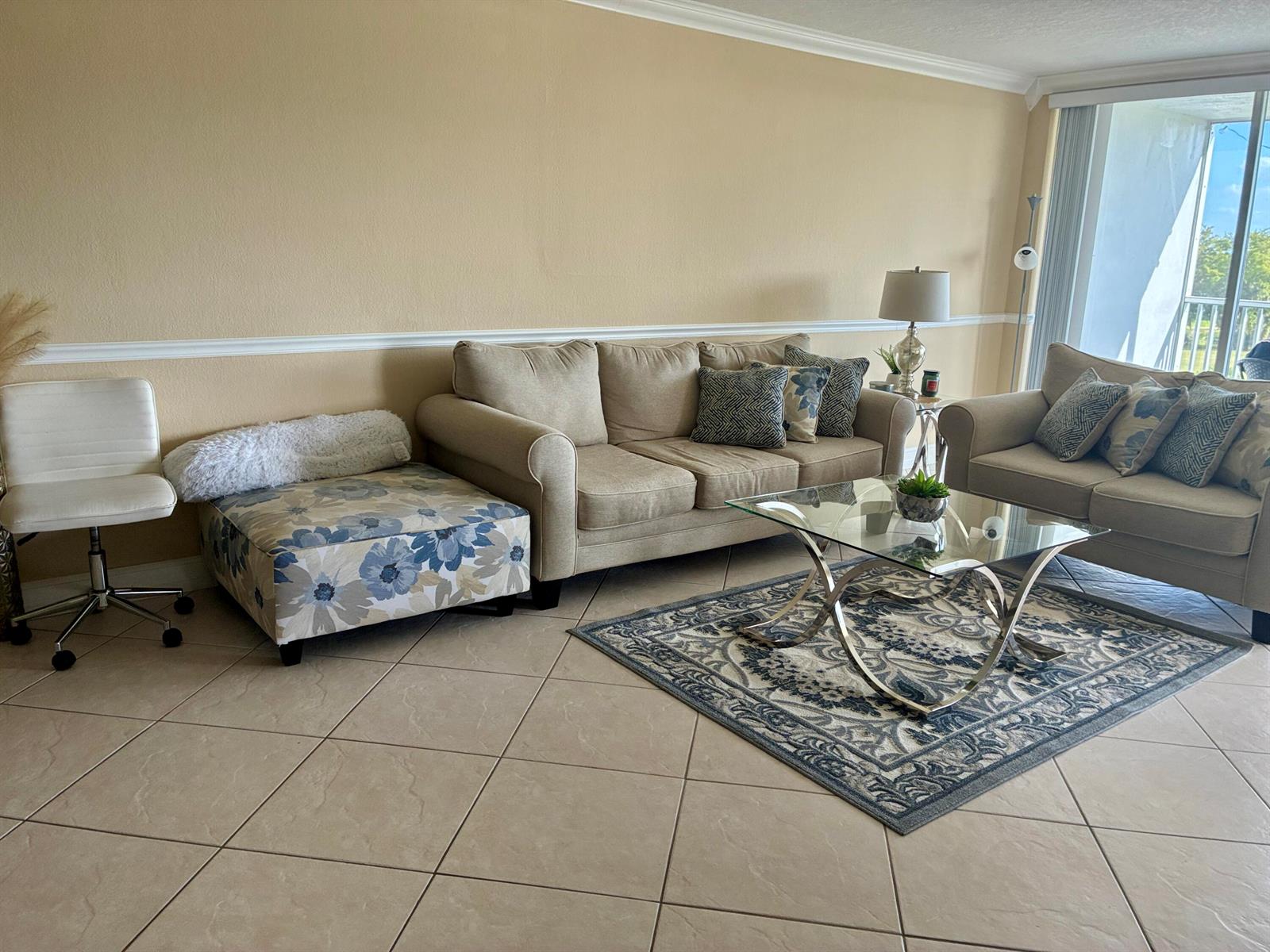 A living room features beige walls, tile flooring, a sofa set, and a glass coffee table — 2691 S Course Drive # 409, Pompano Beach FL 33069, POMPANO BEACH, FL
