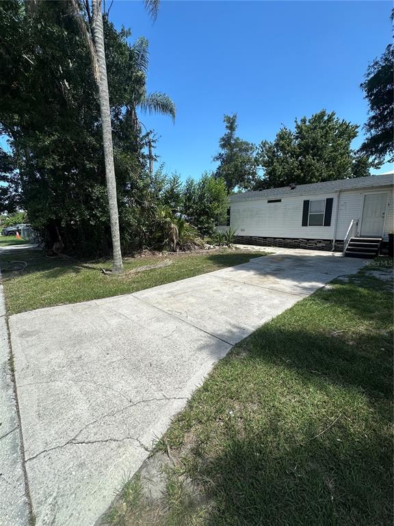A concrete driveway leads to a white mobile home with a small set of stairs — 2594 MCINTOSH DRIVE, LAKELAND, FL
