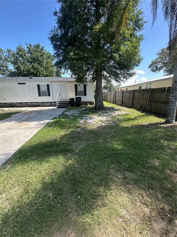 A white mobile home with a concrete driveway and a large tree in the yard — 2594 MCINTOSH DRIVE, LAKELAND, FL